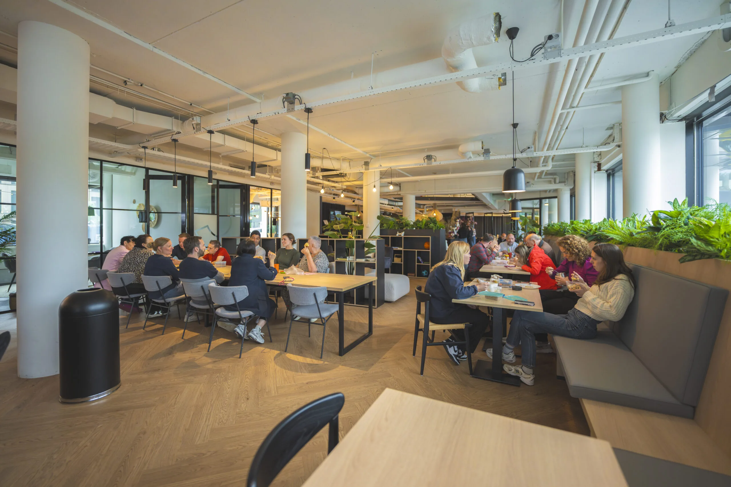 Mensen zitten samen aan tafels in een warme, open ruimte die dienstdoet als sociaal hart.