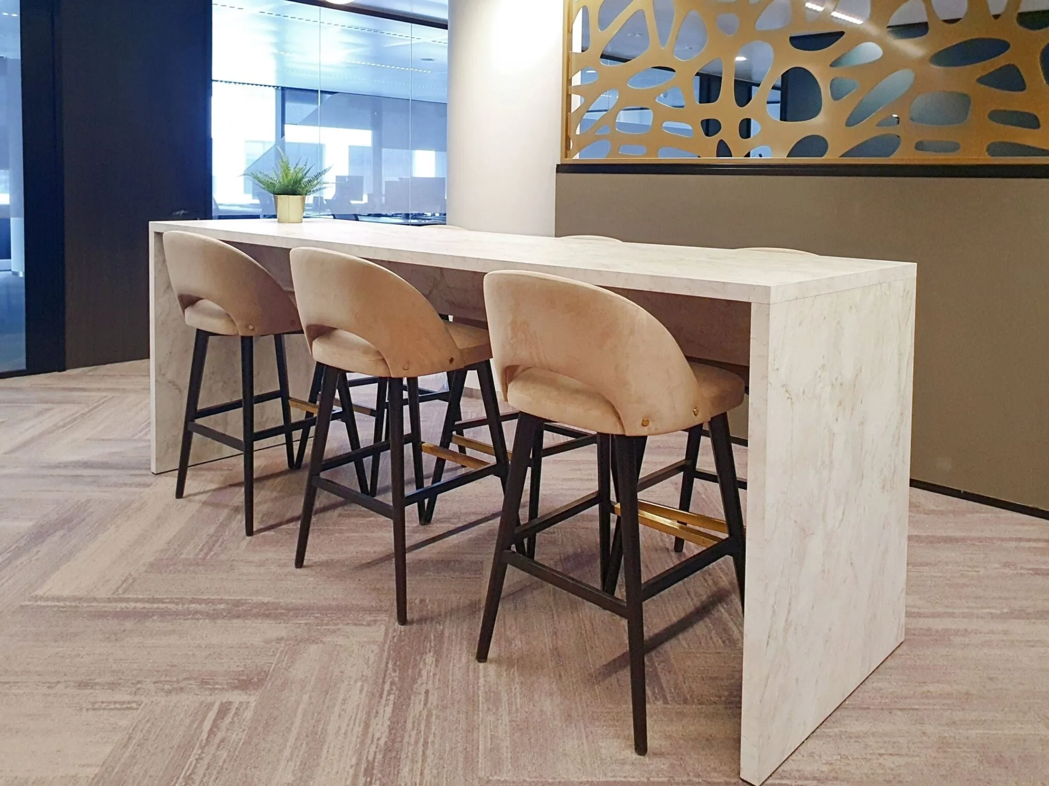 Hoge marmeren tafel met vier beige barkrukken in een modern kantoorinterieur op Stadsplateau 7.