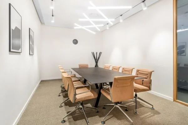 Vergaderruimte met een lange zwarte tafel, bruine stoelen, moderne verlichting en minimalistische kunst aan de muur in Stationsplein 18.