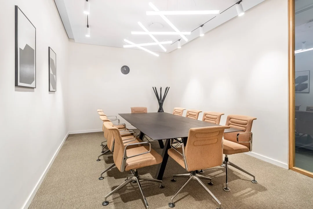 Vergaderruimte met een lange zwarte tafel, bruine stoelen, moderne verlichting en minimalistische kunst aan de muur in Stationsplein 18.
