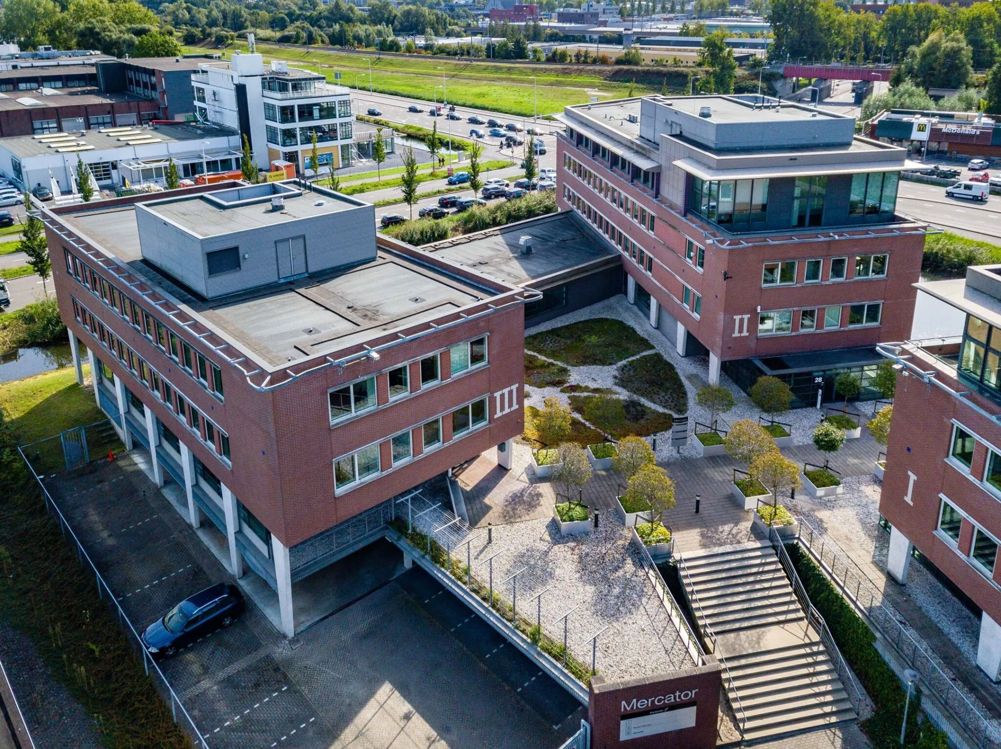 Luchtfoto van het kantoorgebouw Mercator aan de Tielweg 30 met omliggende infrastructuur en parkeergelegenheid.