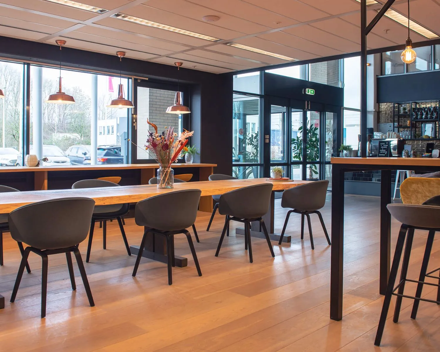 Moderne en sfeervolle kantine in Utrecht met lange houten tafels, zwarte stoelen en grote ramen.