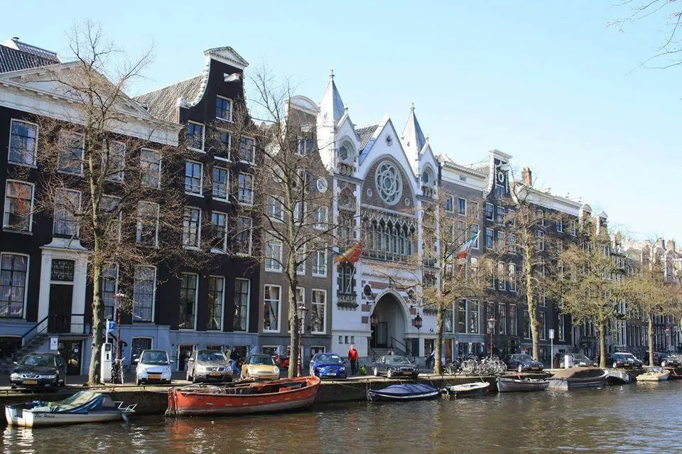 Vooraanzicht van grachtenpanden en de karakteristieke gevel van de voormalige kerk aan een Amsterdamse gracht.