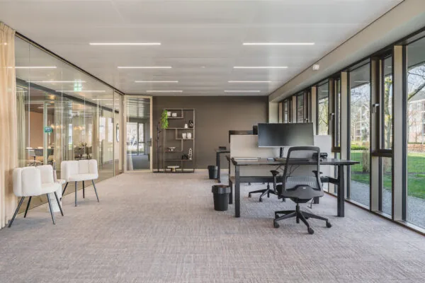 Moderne en licht ingerichte kantoorruimte in Walborg met werkplekken, stoelen en grote ramen met uitzicht op groen.
