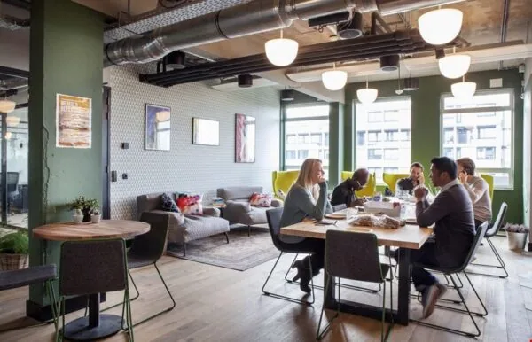 Mensen zitten aan een tafel in een modern ingerichte kantoorruimte aan de Weesperstraat 61-105.