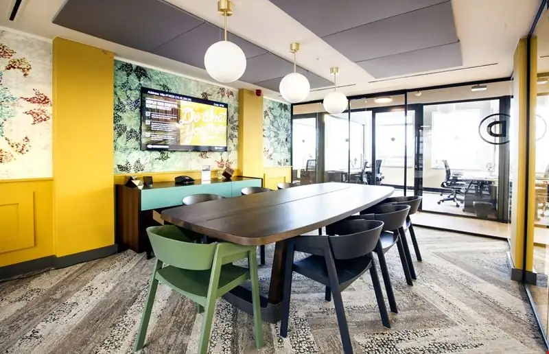 Moderne vergaderruimte in Weesperstaat 61-105 met kleurrijke inrichting, lange houten tafel en glazen wanden.