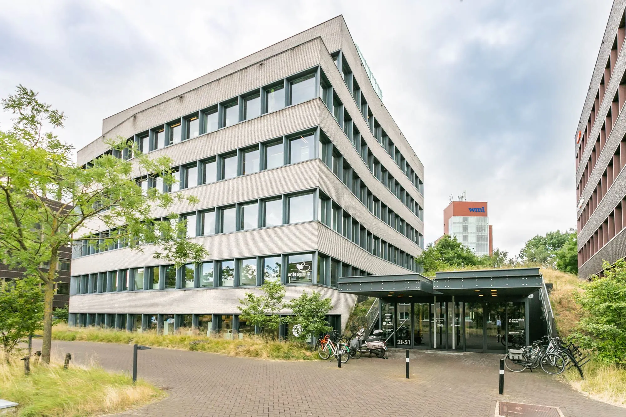 Kantoorgebouw aan het Wim Duisenbergplantsoen 31 met hoofdingang en fietsenrekken op de voorgrond.