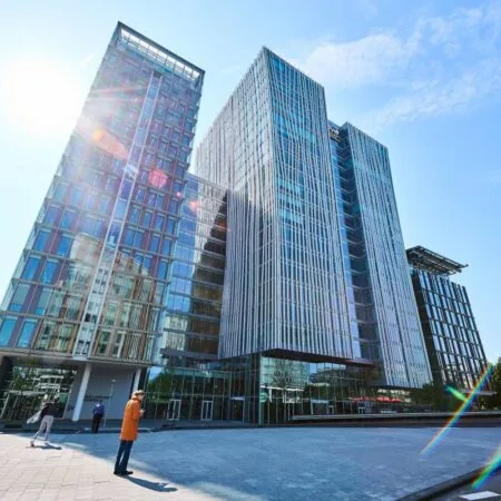 Moderne glasgebouwen met een zonnige hemel en lens flare op de voorgrond.