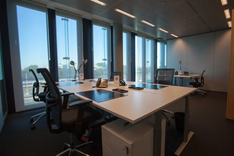Een moderne kantoorruimte met bureaus, stoelen en grote ramen langs de Amstelveenseweg.