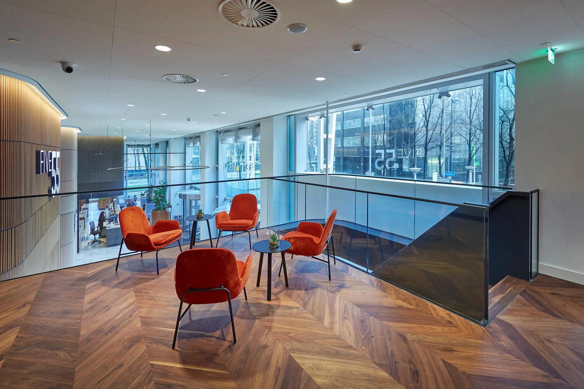 Moderne wachtruimte in Blaak 555 met oranje stoelen, houten vloer en uitzicht op de stad.