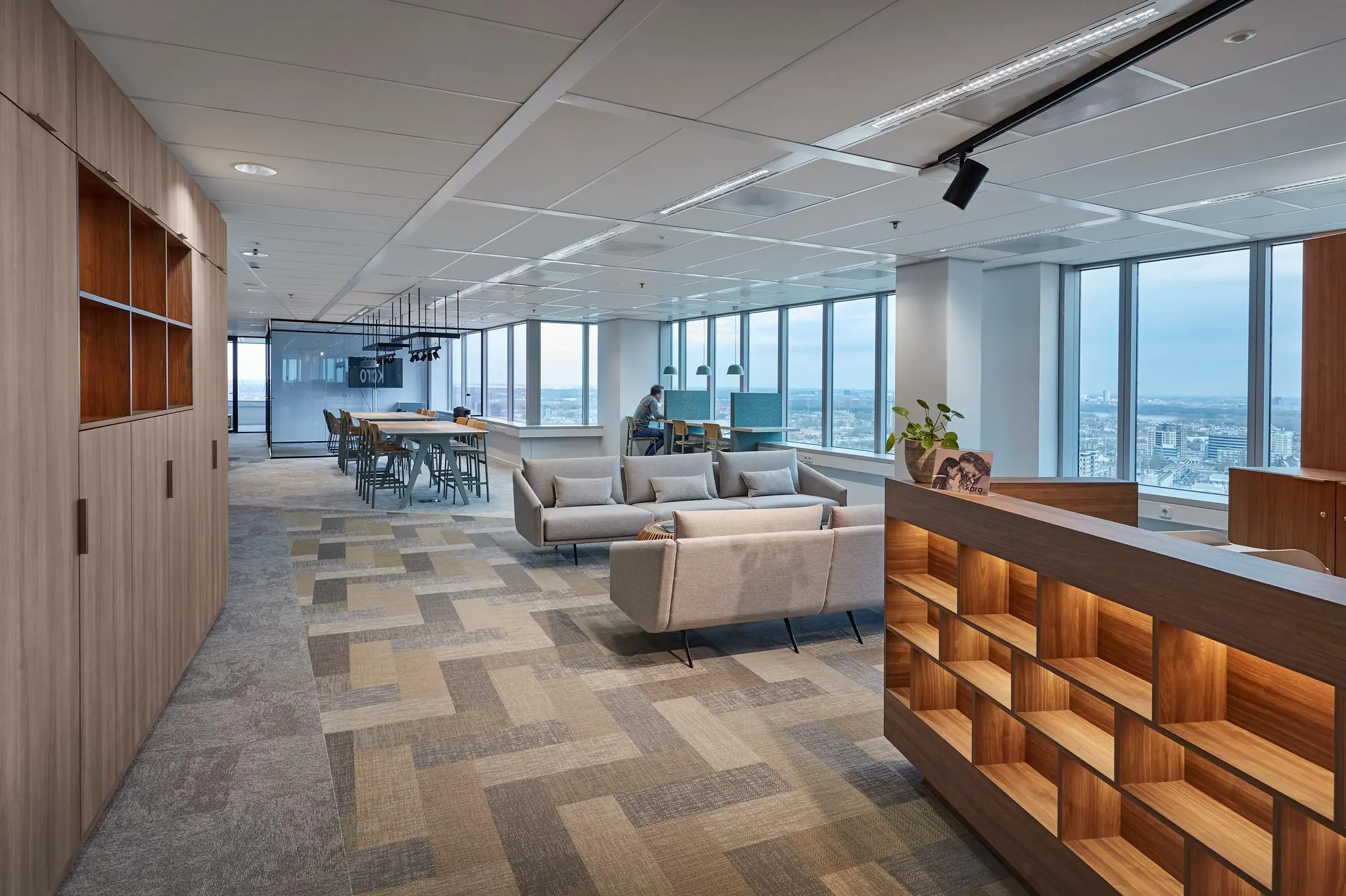 Modern kantoorinterieur in Blaak 555 met zithoeken, werkplekken en panoramisch uitzicht over de stad.