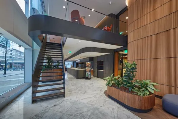 Moderne entreehal van Blaak 555 met een open trap, binnengroen en stijlvolle houten afwerkingen.