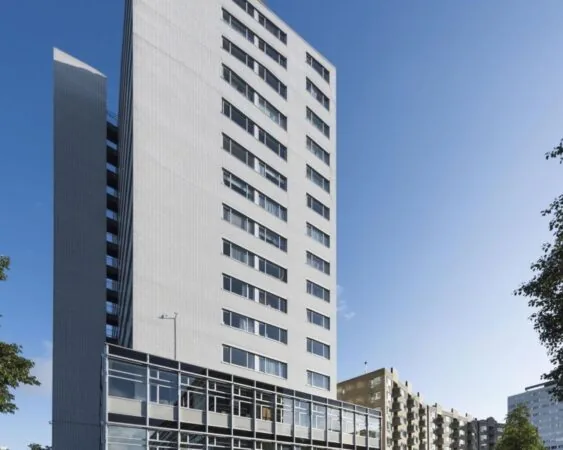 Hoog wit appartementencomplex met moderne gevel, gefotografeerd op een zonnige dag.