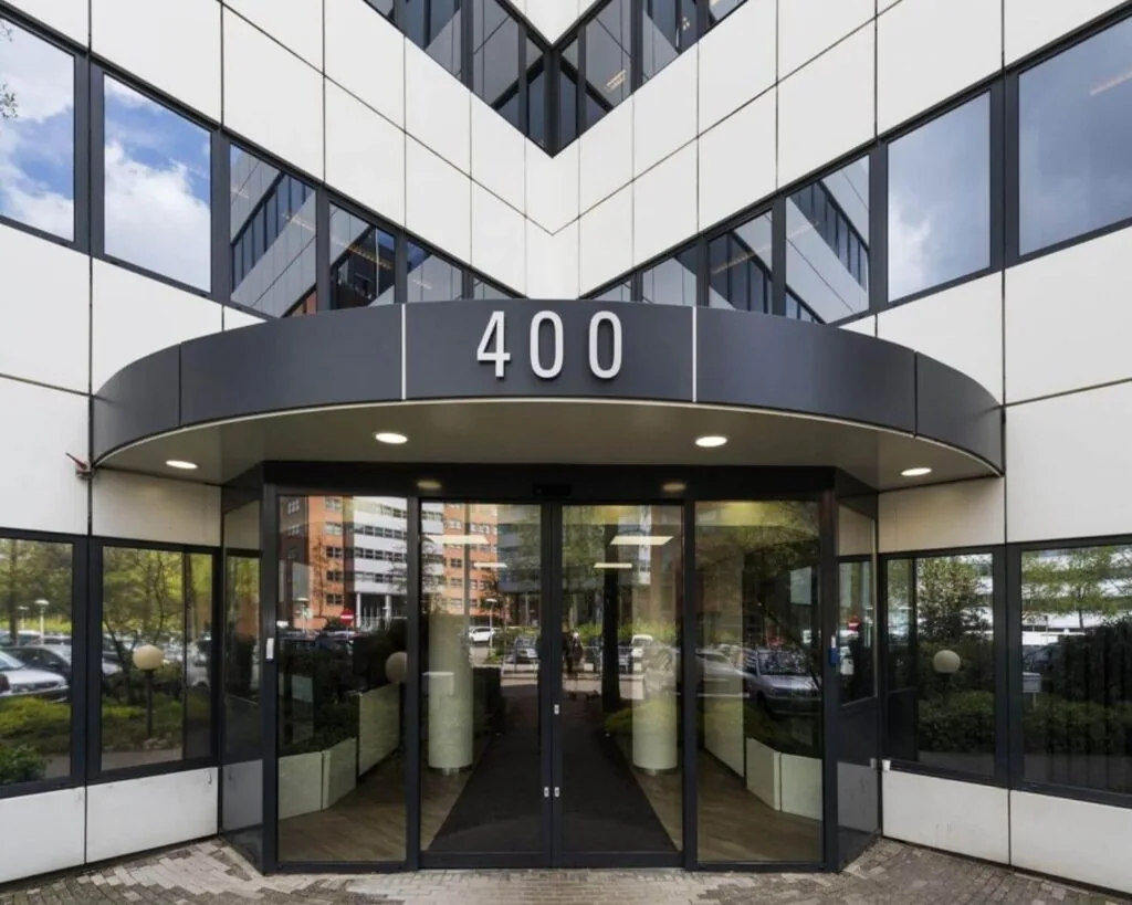 Ingang van een modern kantoorgebouw met het nummer 400 boven de deur.