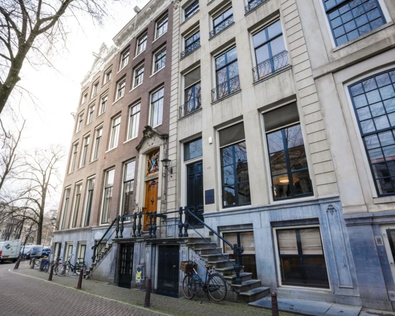 Gevel van een klassiek Amsterdams herenhuis met trapgevel en fietsen geparkeerd langs de gracht.