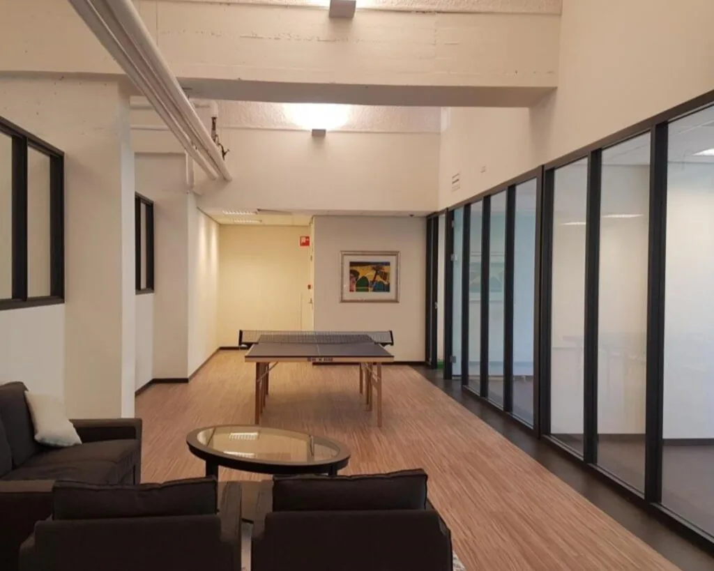 Moderne kantoorruimte met een zithoek en een pingpongtafel in het midden van de ruimte.