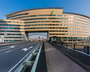 Kantoorgebouw van Nationale-Nederlanden in Rotterdam met boog over de straat en moderne glazen gevel.