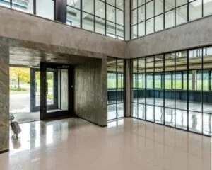 Moderne, lichte entreehal met glazen wanden en glanzende vloer in een kantoorgebouw.