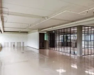 Leegstaand kantoorpand met glazenschuifwanden en betonnen vloer.