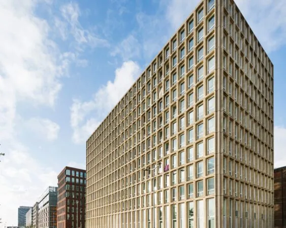 Modern rechthoekig kantoorgebouw met een gevel van betonnen raamkozijnen in een stedelijke omgeving.