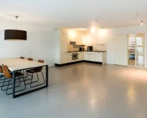 Moderne, minimalistisch ingerichte open keuken met eettafel en zes stoelen in een ruime, lichte kamer.