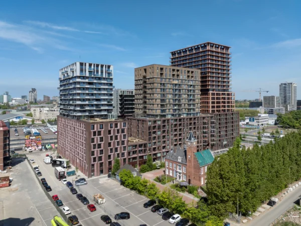 Modern residential high-rises in the Binckhorst district of The Hague with a historic brick building in the foreground.