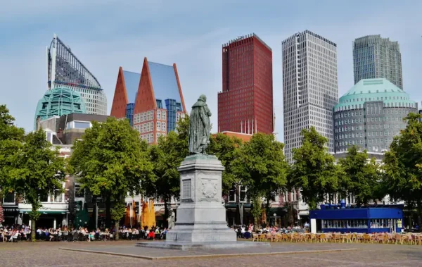 Statue of Johan de Witt in The Hague city center with modern high-rise buildings in the background.