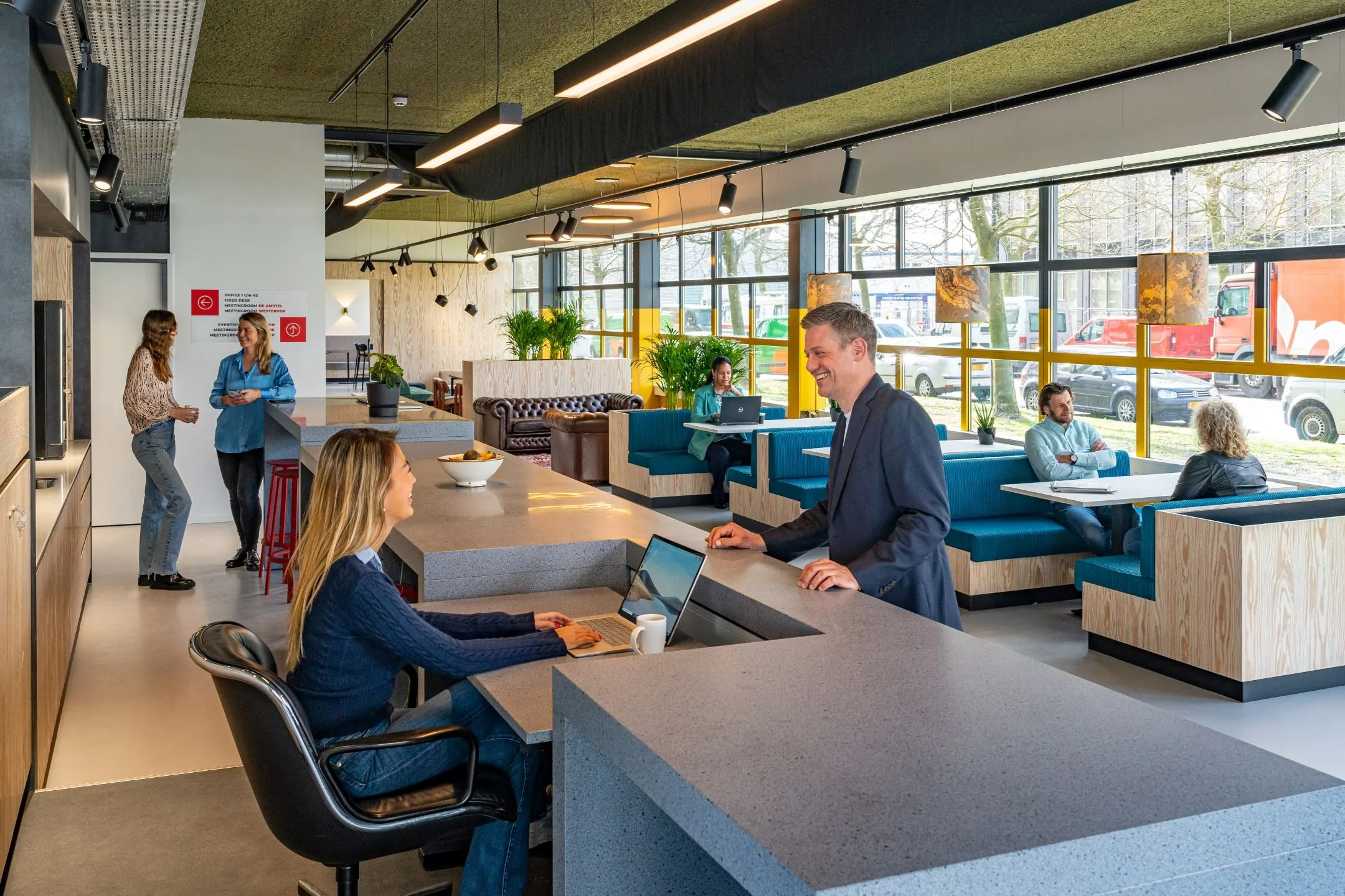 Moderne kantoorruimte aan de Disketteweg 14 met een receptiebalie, werkplekken en mensen in gesprek.