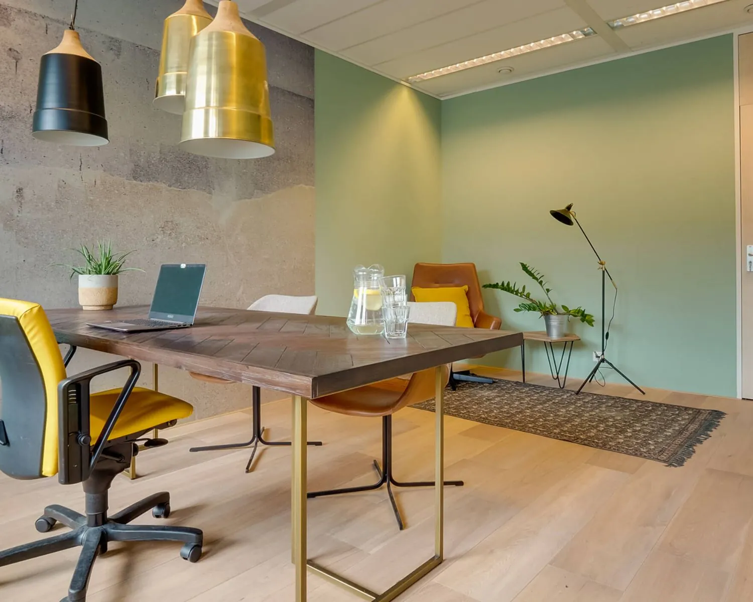 Modern kantoorinterieur met houten tafel, designstoelen, laptop en sfeervolle verlichting.