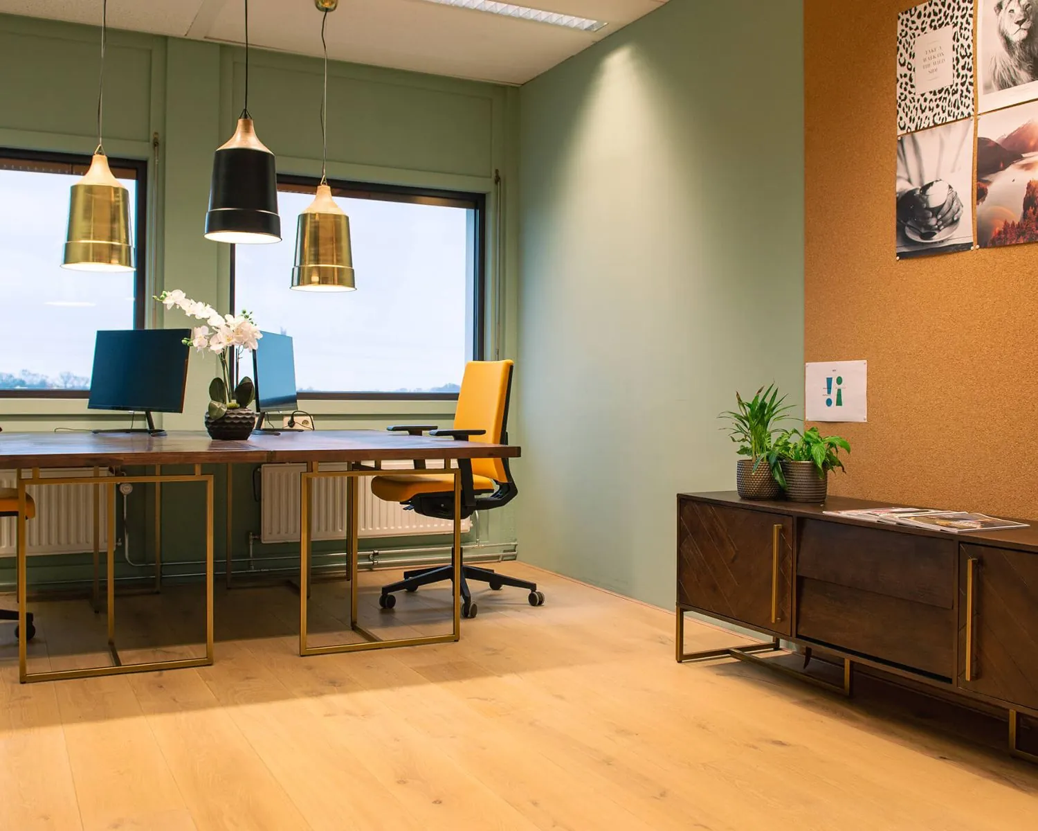 Modern kantoorinterieur met houten vloer, gele bureaustoelen, groene muren en decoratieve planten.