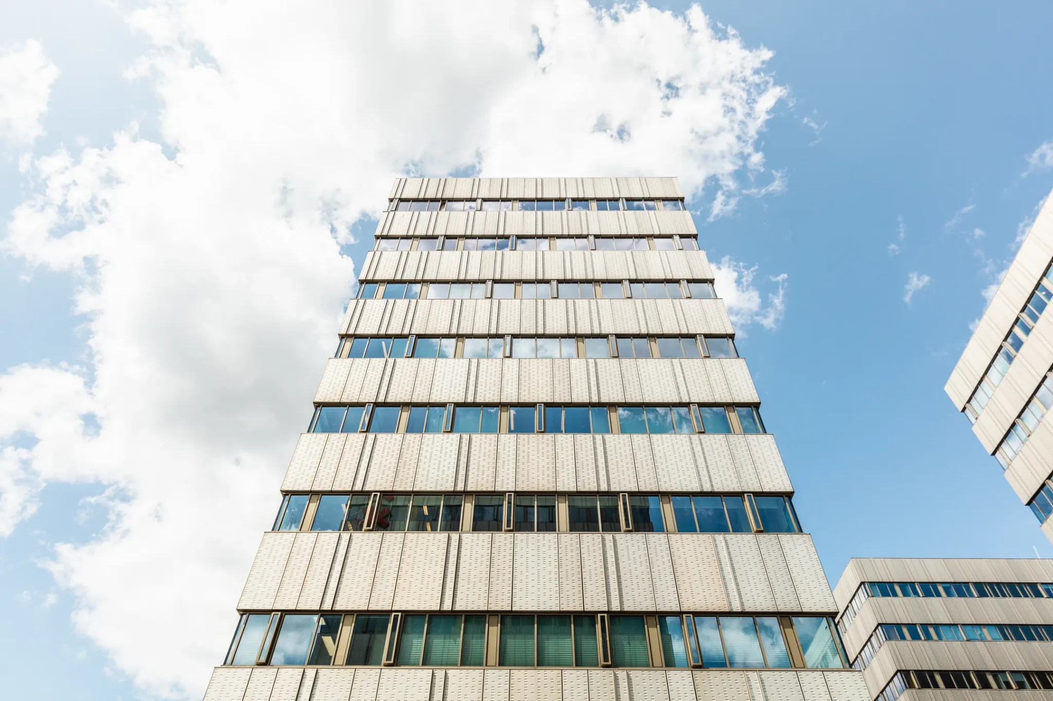 Voorgevel van het moderne kantoorgebouw aan Herengracht 204, gezien vanaf de straat tegen een blauwe lucht.
