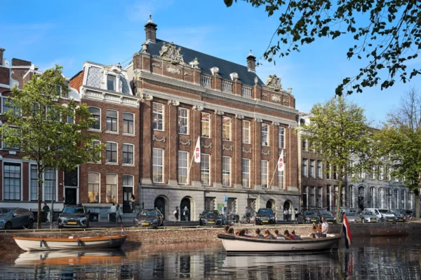 Monumentaal pand aan de Herengracht 206 in Amsterdam, gezien vanaf de overzijde van de gracht met een varende rondvaartboot op de voorgrond.
