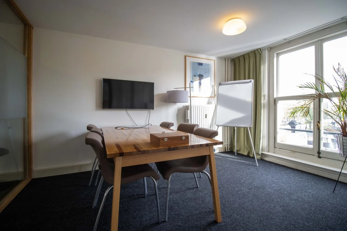 Vergaderruimte aan de Nieuwe Herengracht 8 in Amsterdam met houten tafel, flatscreen, flipover en uitzicht op de gracht.