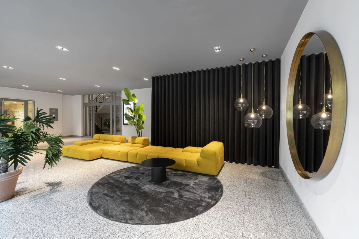 Moderne kantoorruimte met een gele bank, grote spiegel, en planten in de Van Boshuizenstraat, Amsterdam.
