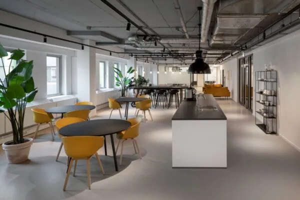 Moderne kantoorruimte met gele stoelen, een zwarte tafel en veel lichtinval aan de Van Boshuizenstraat 8 in Amsterdam.