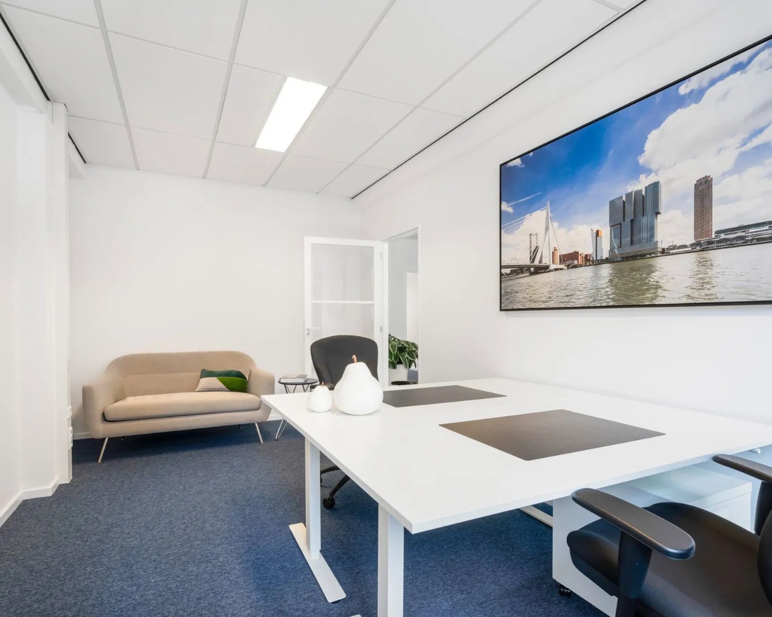 Moderne kantoorruimte aan de Posthoornstraat 17 in Rotterdam met bureaus, zithoek en een grote foto van de Rotterdamse skyline aan de muur.