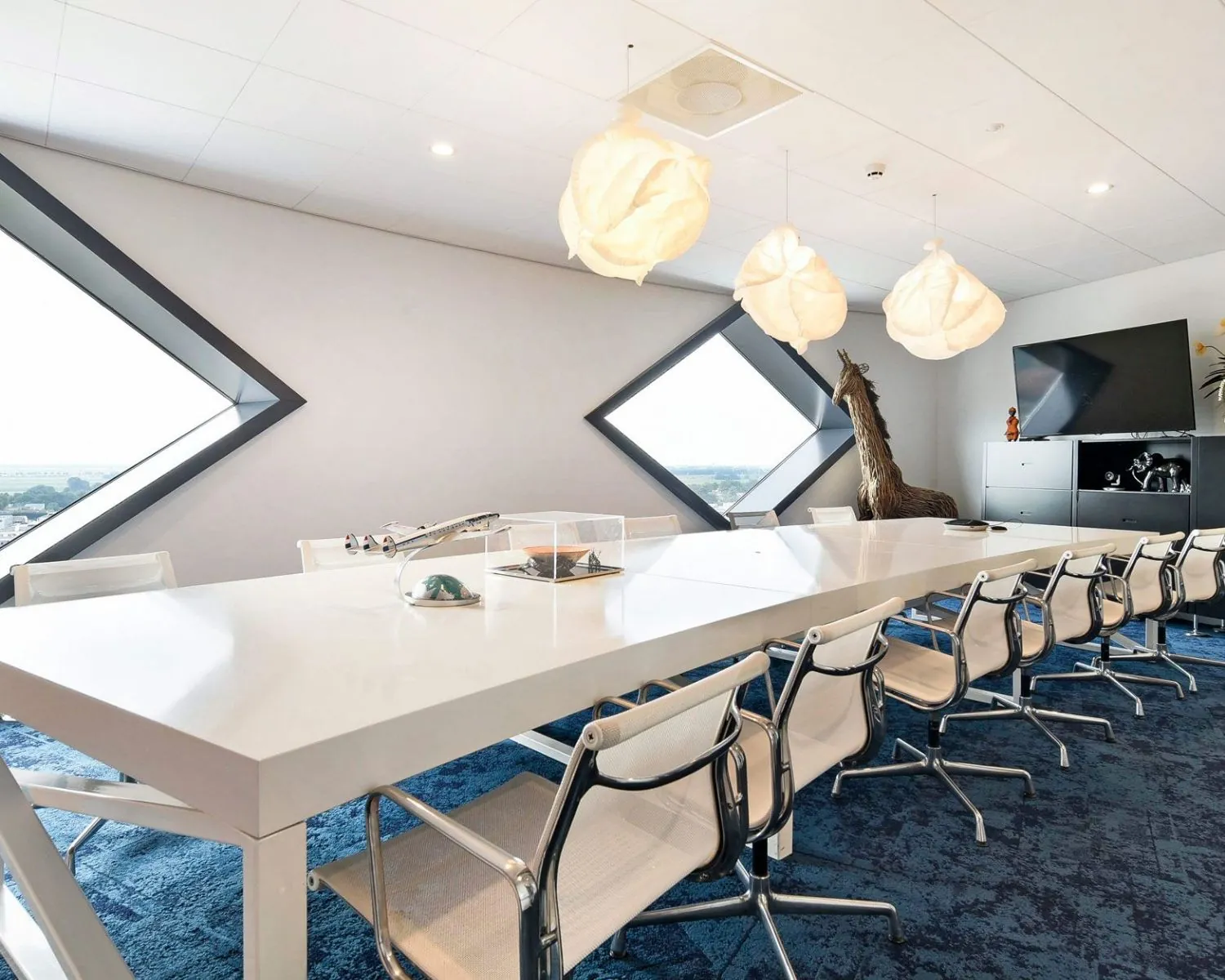 Moderne vergaderruimte in SugarCity Halfweg met lange witte tafel, designstoelen en grote ruitvormige ramen.
