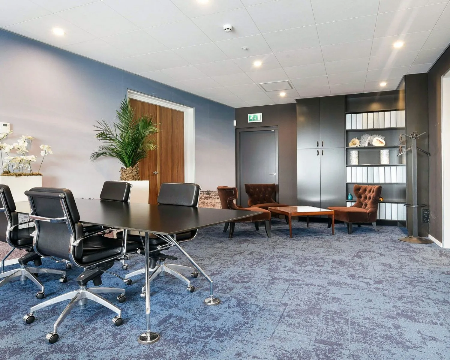 Moderne kantoorruimte in SugarCity Halfweg met vergadertafel, designstoelen en loungehoek met bruine fauteuils.