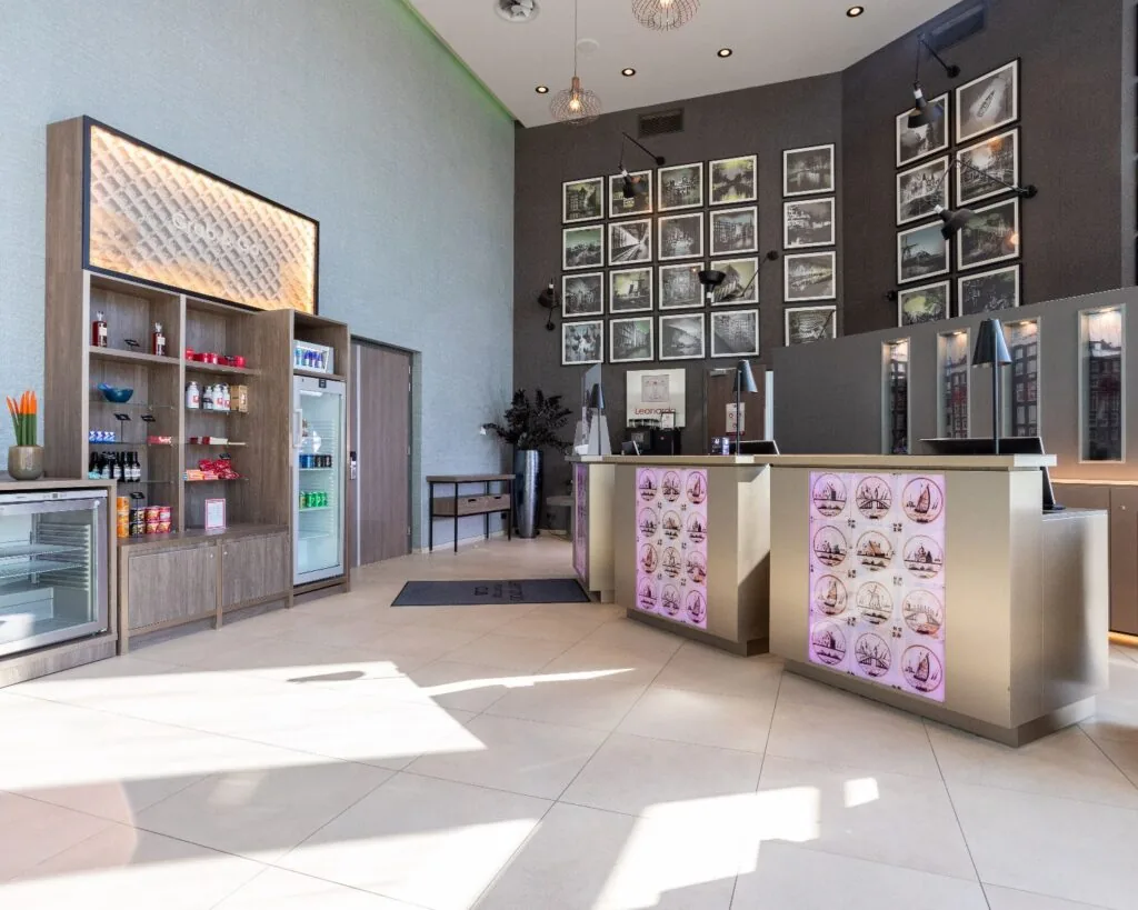 Moderne receptieruimte in het Leonardo Royal Hotel aan de Paul van Vlissingenstraat 24 in Amsterdam met displays, foto's en een minimarkt.
