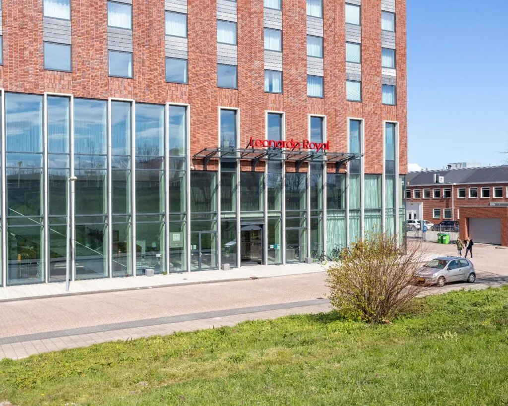 Vooraanzicht van een modern kantoorgebouw met grote glazen ramen, gelegen in Amsterdam bij het Leonardo Royal Hotel.