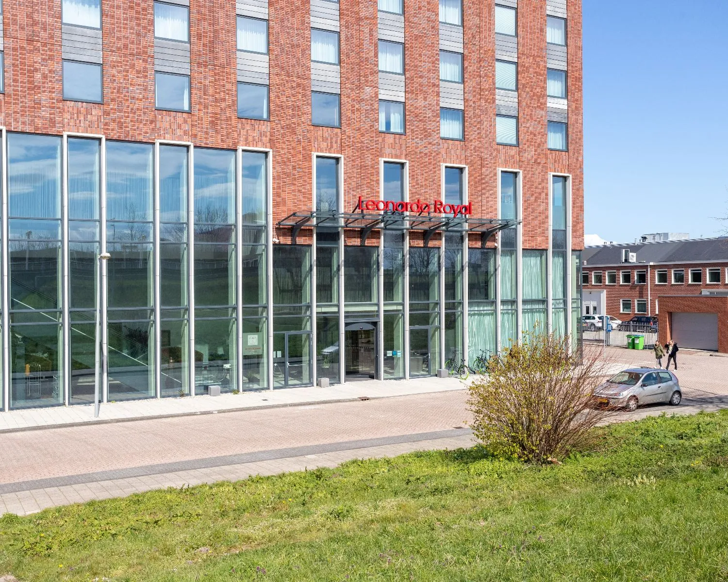 Voorgevel van het Leonardo Royal Hotel aan de Paul van Vlissingenstraat 24-8 in Amsterdam met moderne glazen entree.