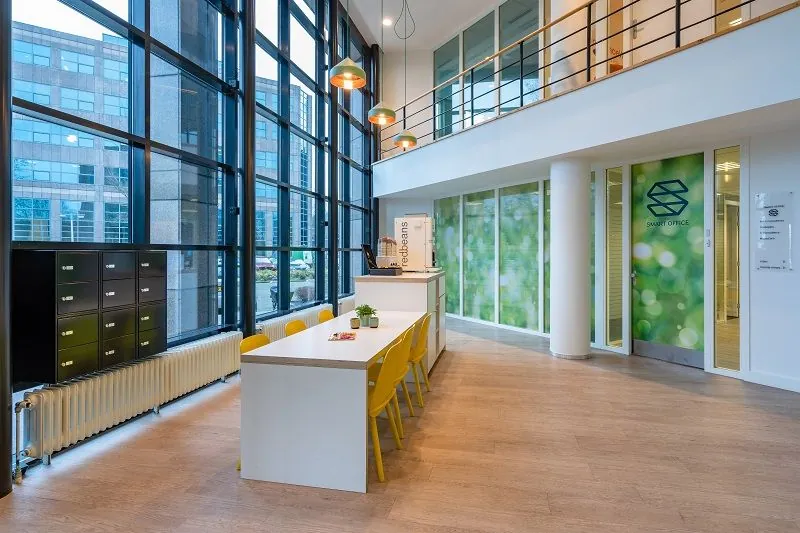 Moderne, lichte kantoorruimte met hoge ramen, kleurrijke zithoeken en de entree van Smart Office aan de Overschiestraat 186 in Amsterdam.