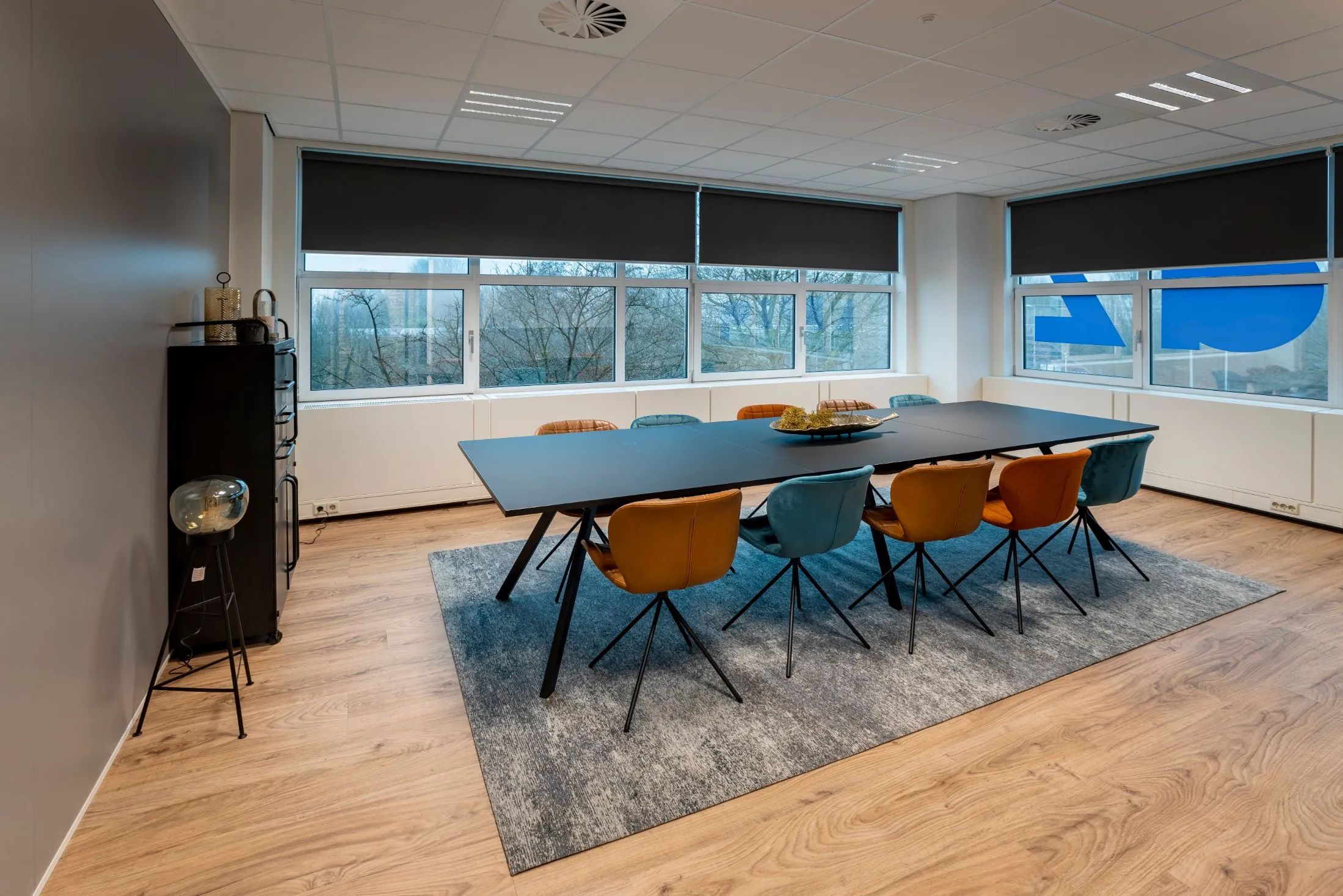 Moderne vergaderruimte met lange zwarte tafel en kleurrijke stoelen in kantoor aan de Overschiestraat 186 in Amsterdam.