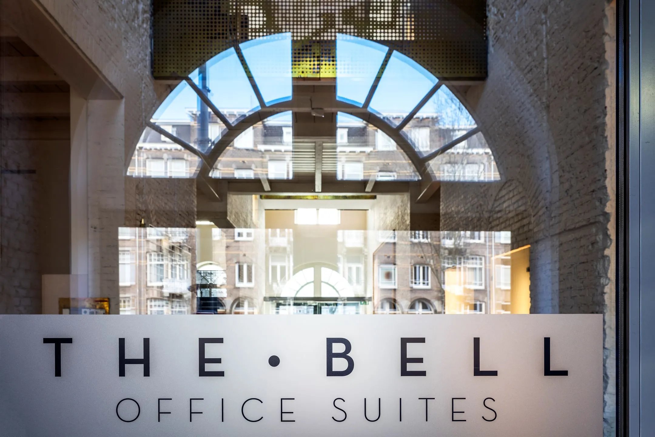 Glazen entree met logo van The Bell Office Suites aan de Sarphatistraat 370 in Amsterdam.