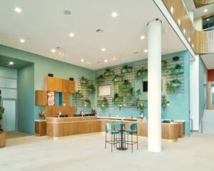 Moderne en lichte entree met receptiebalie en groene wand in een kantoorpand aan het Mercuriusplein in Hoofddorp.