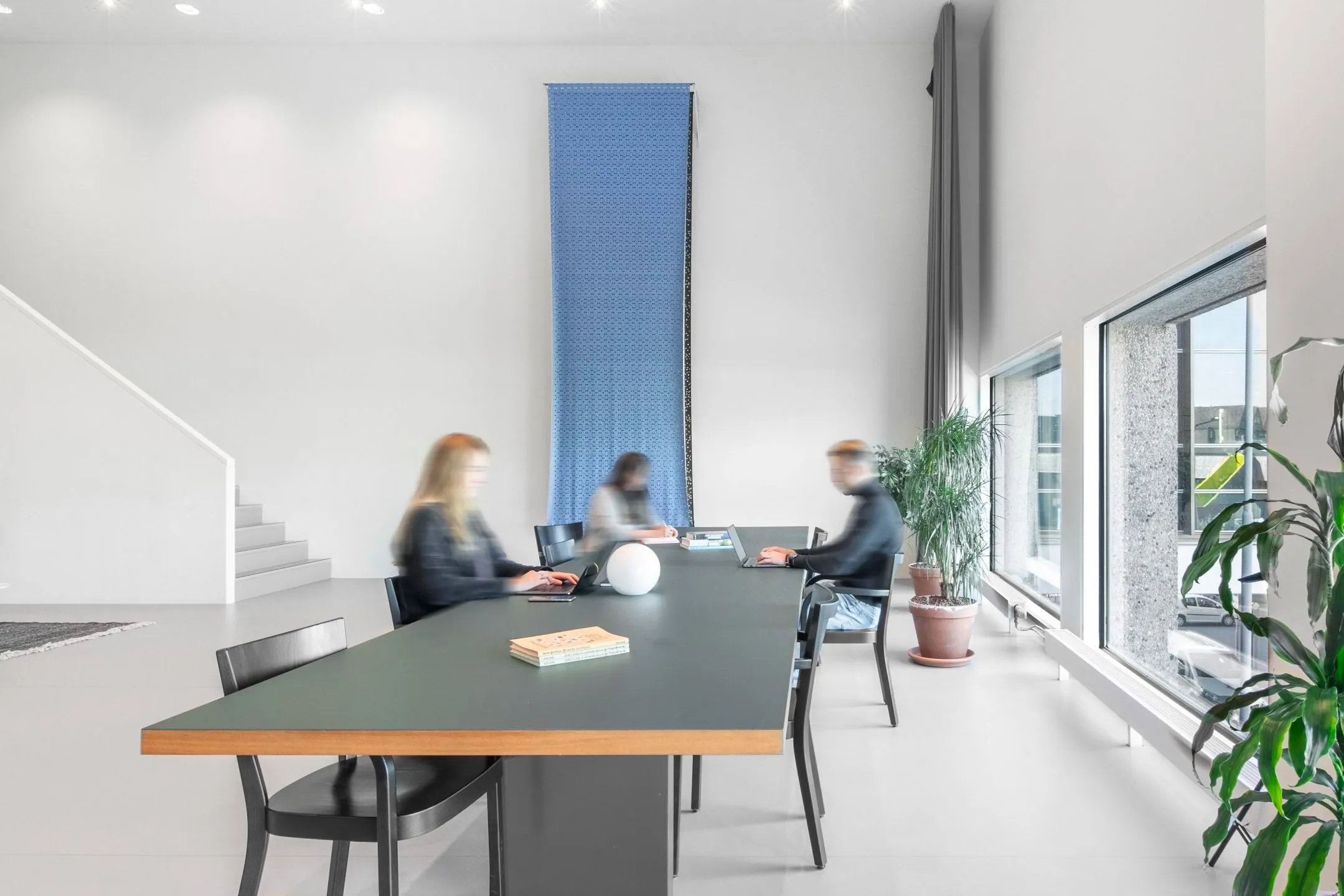 Moderne kantoorruimte in Rotterdam Hofplein 20 met grote ramen, minimalistische inrichting en werkende mensen aan een lange tafel.