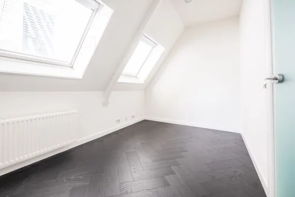 Lichte kantoorruimte aan de Sophialaan 21 in Amsterdam met dakramen en donker visgraat houten vloer.