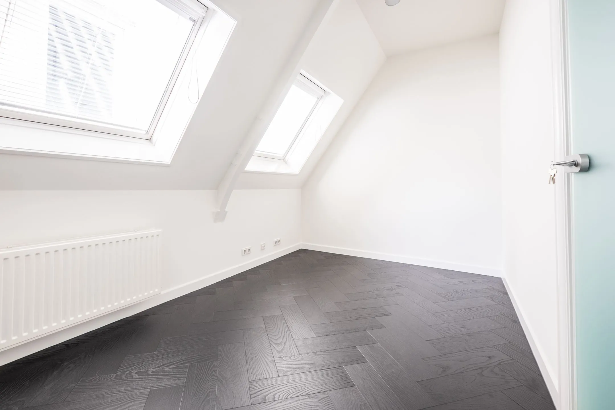 Lichte kantoorruimte aan de Sophialaan 21 in Amsterdam met dakramen en donker visgraat houten vloer.
