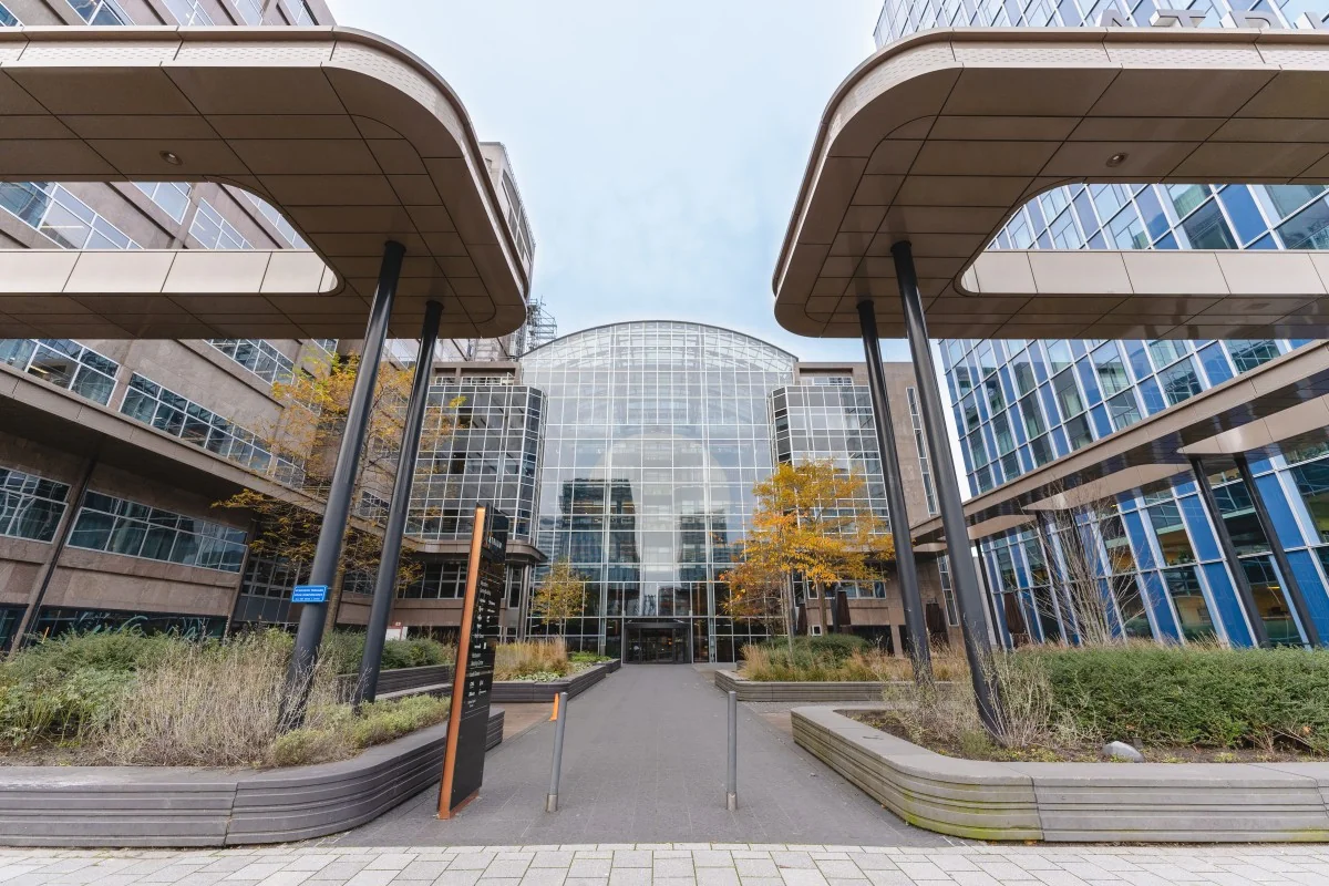 Vooraanzicht van een moderne kantoorruimte op de Strawinskylaan, omringd door glazen en metalen architectuur met herfstkleuren in de beplanting.
