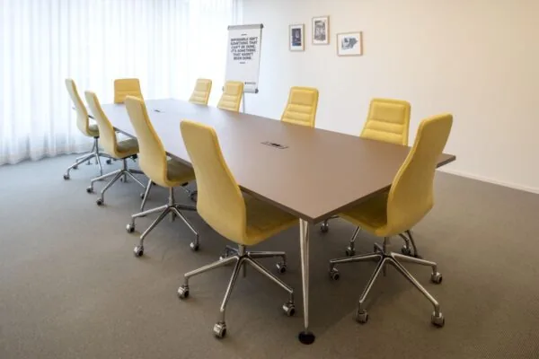Vergaderruimte met een lange tafel en gele stoelen in een kantoor aan de Vijzelstraat 11 in Amsterdam.